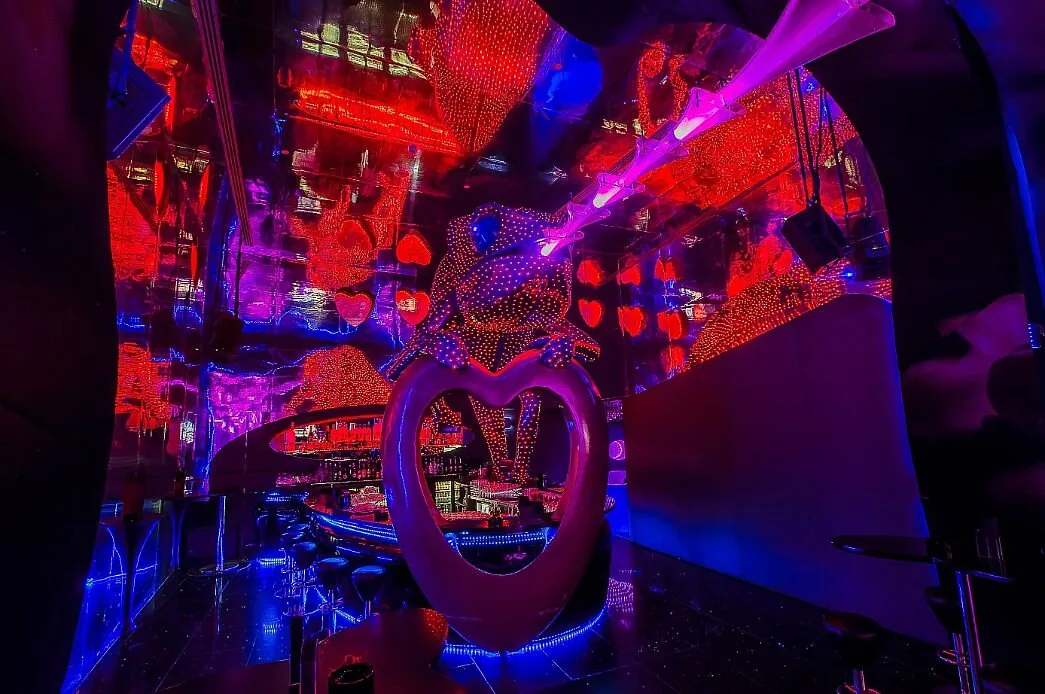 The Chameleon Heart sculpture framed by laser beams and red light inside Chameleon Club Dubai