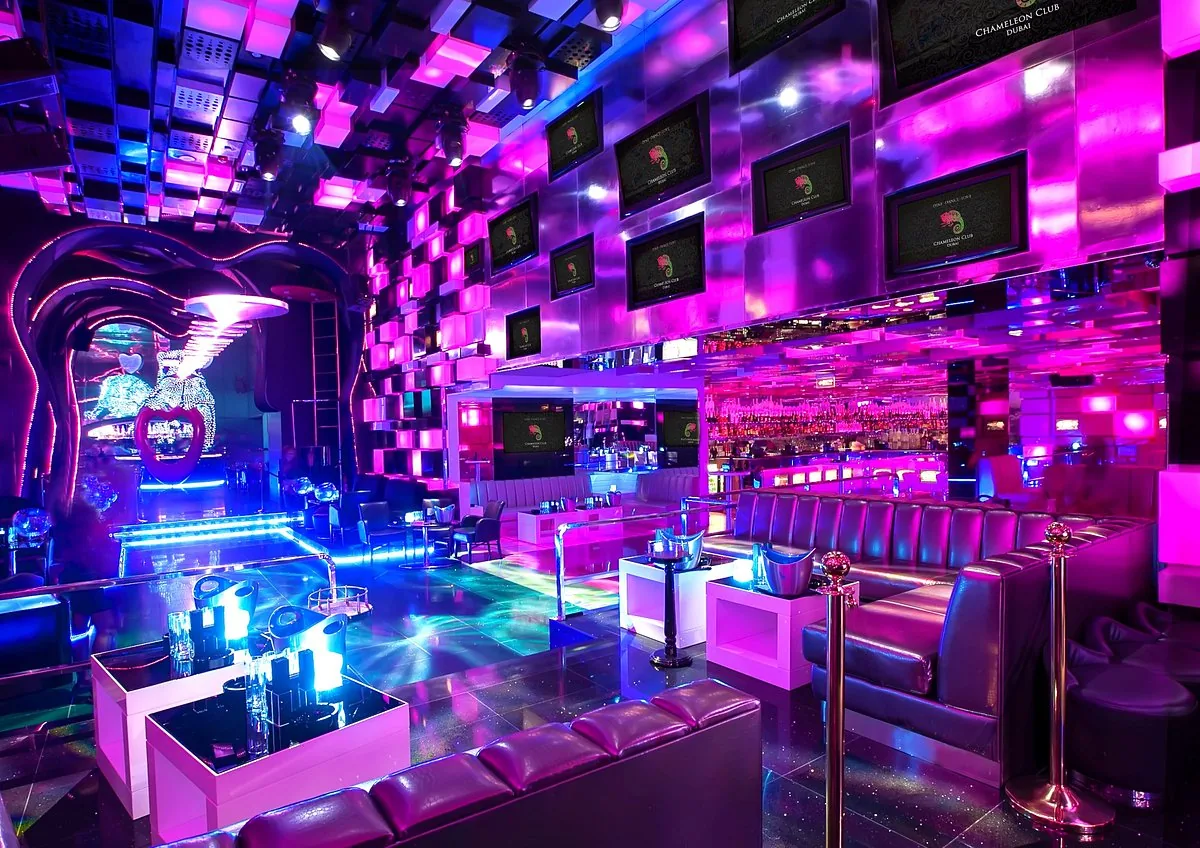 VIP lounge at Chameleon Club Dubai with white booths, magenta LED walls and glowing tables